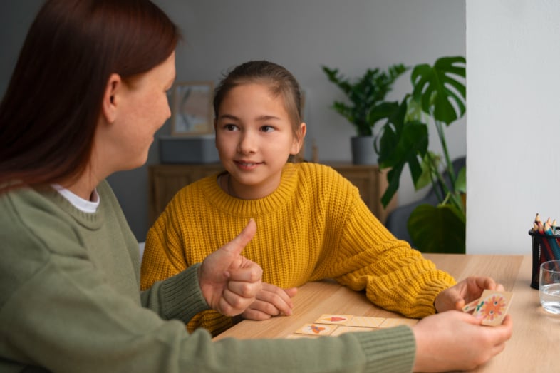 Adolescent girl in a yellow sweater playing a game with her mom